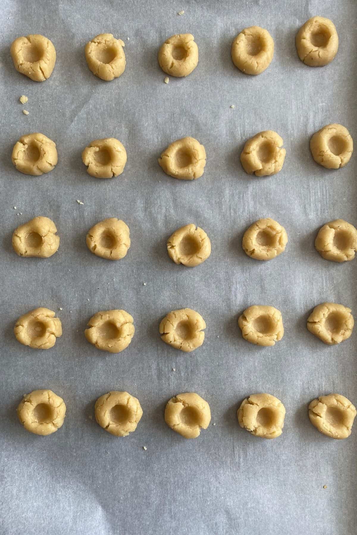 An overhead view of thumbprinted cookie dough before jam is placed