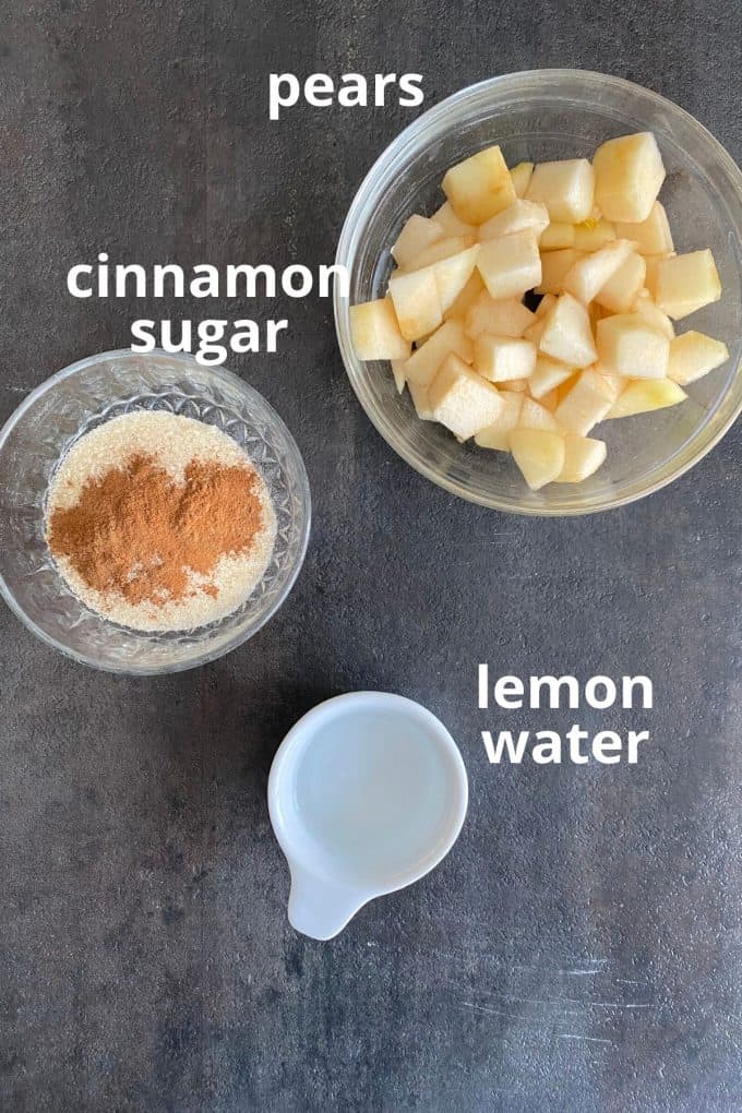 An overhead view of the ingredients to make pear jam; cinnamon, sugar, chopped pears, lemon juice, water