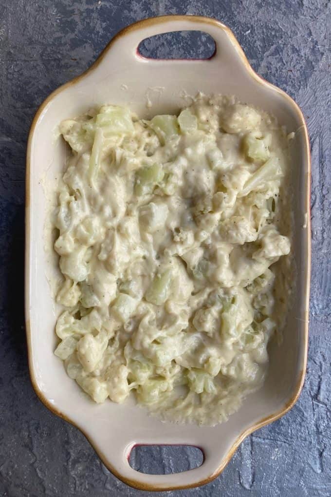 An overhead view of cauliflower mixed with bechamel sauce in a baking dish