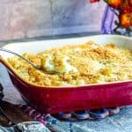 A tilted view of a red baking dish with cauliflower gratin