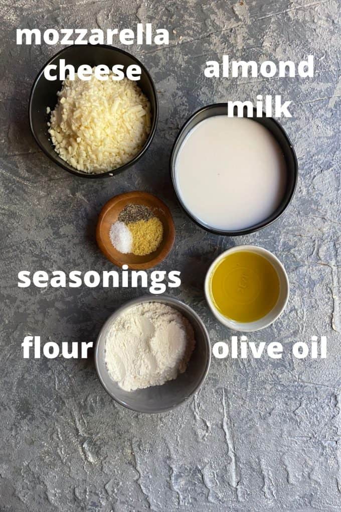 An overhead view of ingredients to make cauliflower gratin; mozzarella cheese, almond milk, seasonings, olive oil, and flour