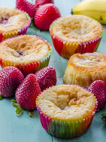 Side view of strawberry banana muffins on a green wood surface