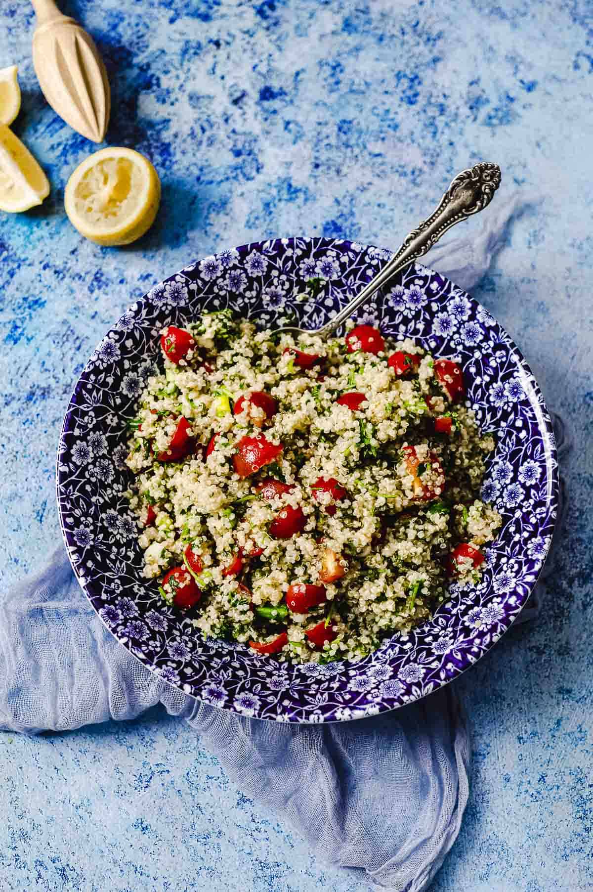 overhead closer view of a bowl of quinoa tabbouleh next to a cut lemon