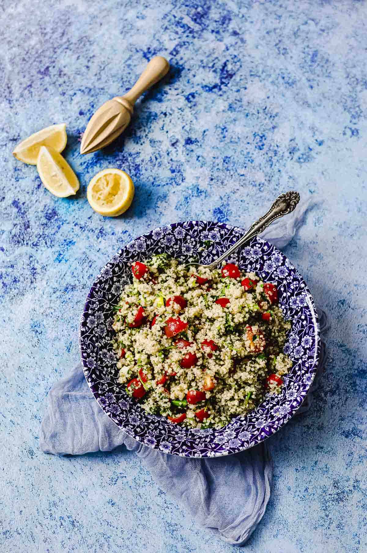 overhead view of a bowl of quinoa tabbouleh next to a cut lemon
