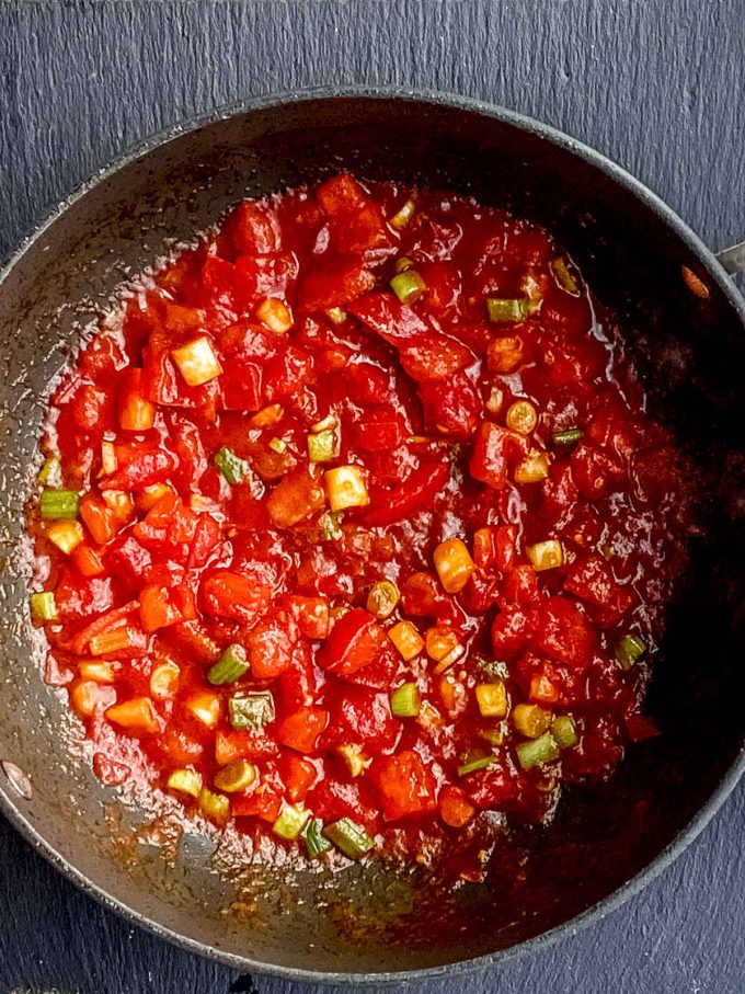 Tomato paste, fresh diced tomatoes and scallions cooking in a pan
