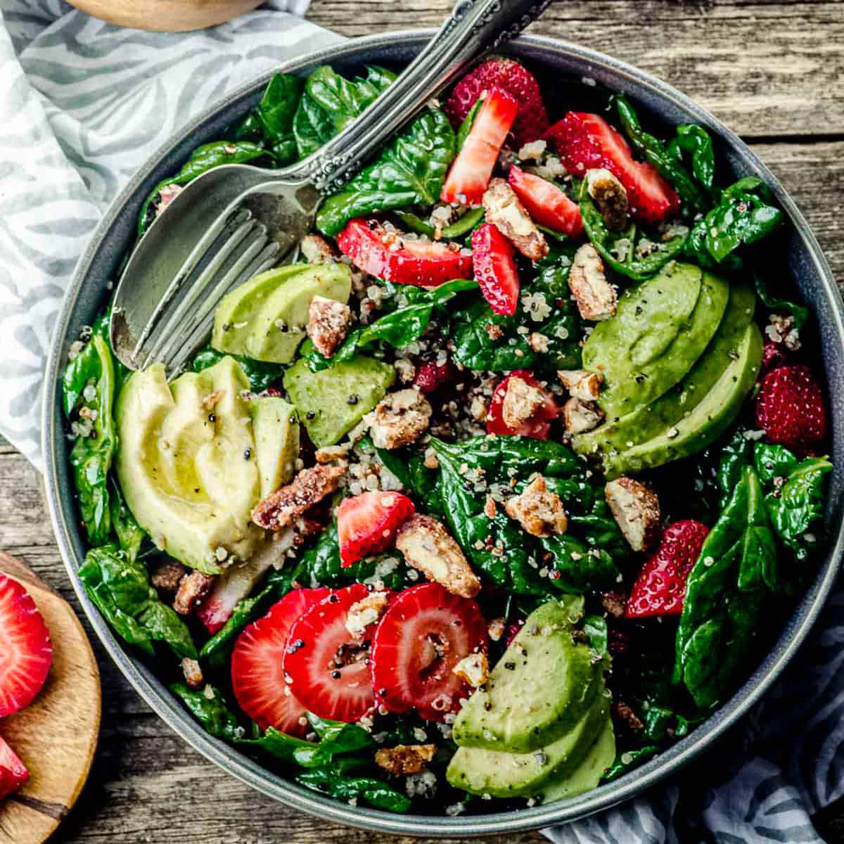 bird's eye view of a plate of spinach salad with strawberries, avocado, and candied pecans