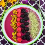 Bird's eye view of a magenta smoothie bowl topped with pistachios, raspberries, blackberries, and hemp seeds