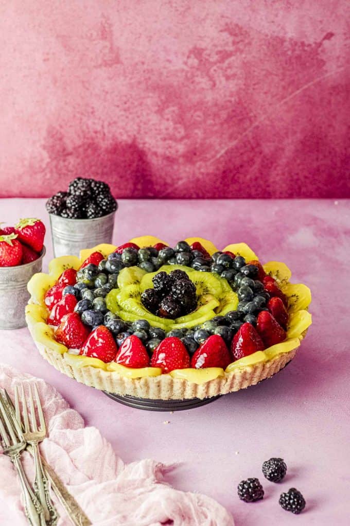 Side view of a fruit tart with a pink background