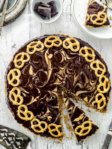 Bird's eye view of a whole pretzel chocolate peanut butter tart with a slice cut up
