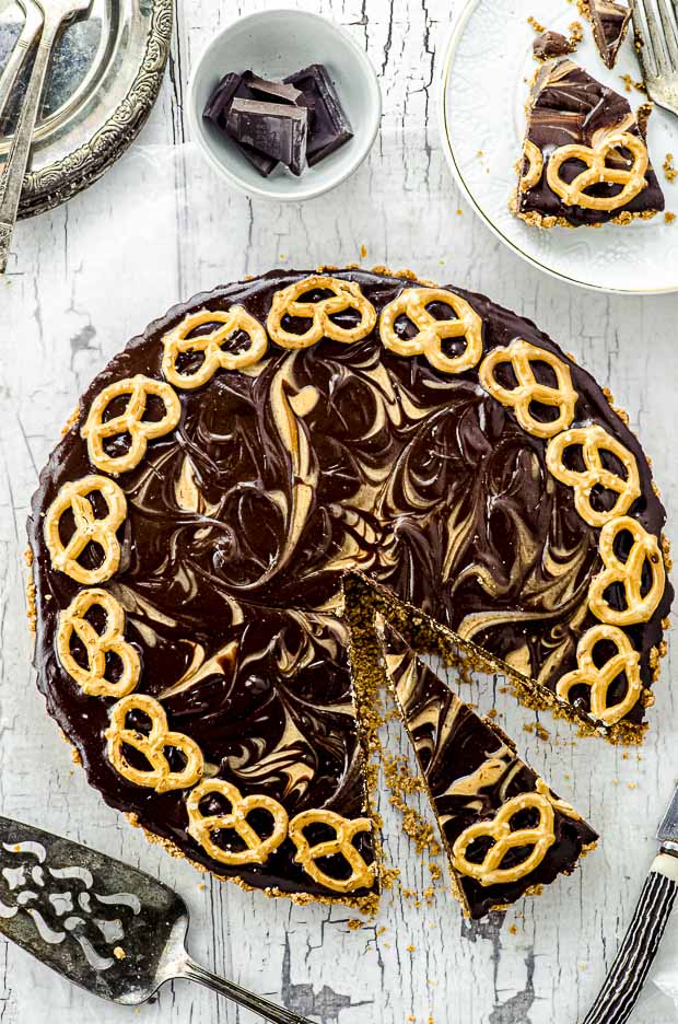 Bird's eye view of a whole pretzel chocolate peanut butter tart with a slice cut up