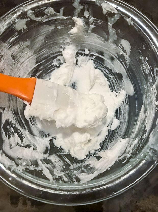 Glass bowl with creamed coconut oil and sugar with a white an orange spatula