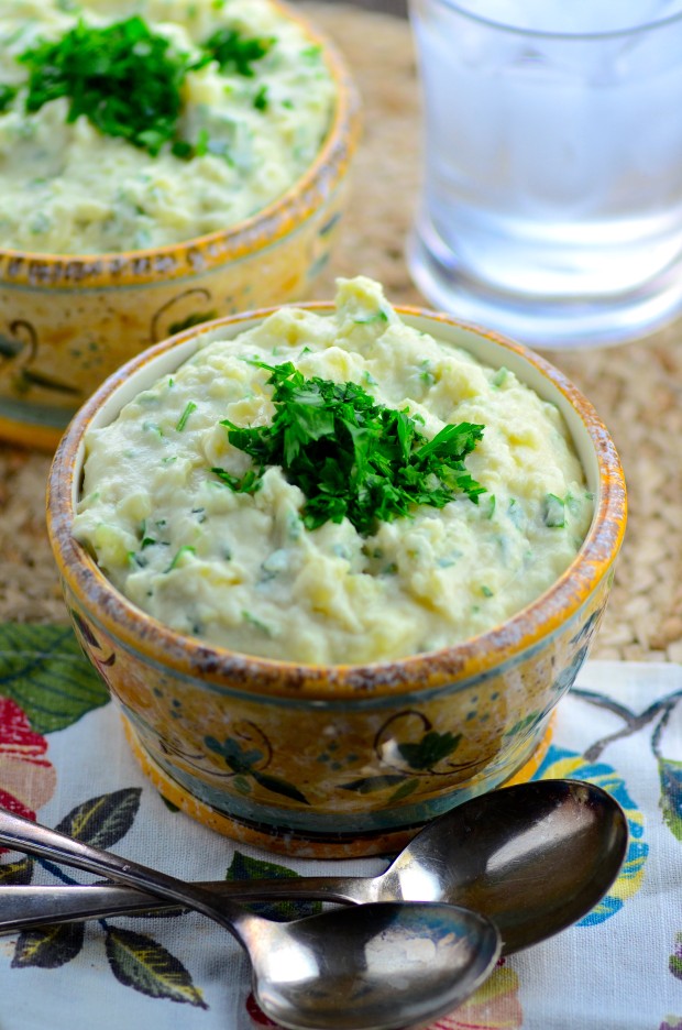 45 degree view of a bowl filled with tahini mashed potatoes topped with green fresh parsley