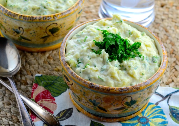 A bowl filled to the top with Tehina Mashed Potatoes topped with green chopped parsley