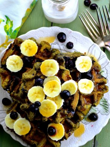 Bird's eye view of a plate with e matcha waffles topped with fresh bananas and blueberries