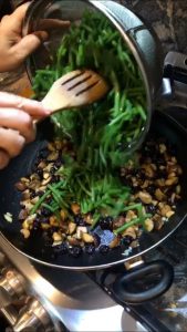 Placing green beans in a pan with chestnuts and cherries