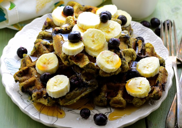 Side view of  a plate with e matcha waffles topped with fresh bananas and blueberries
