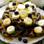 Side view of a plate with e matcha waffles topped with fresh bananas and blueberries