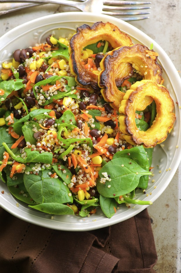 Overhead View of a spinach salad with quinoa, black beans and roasted delicate squash