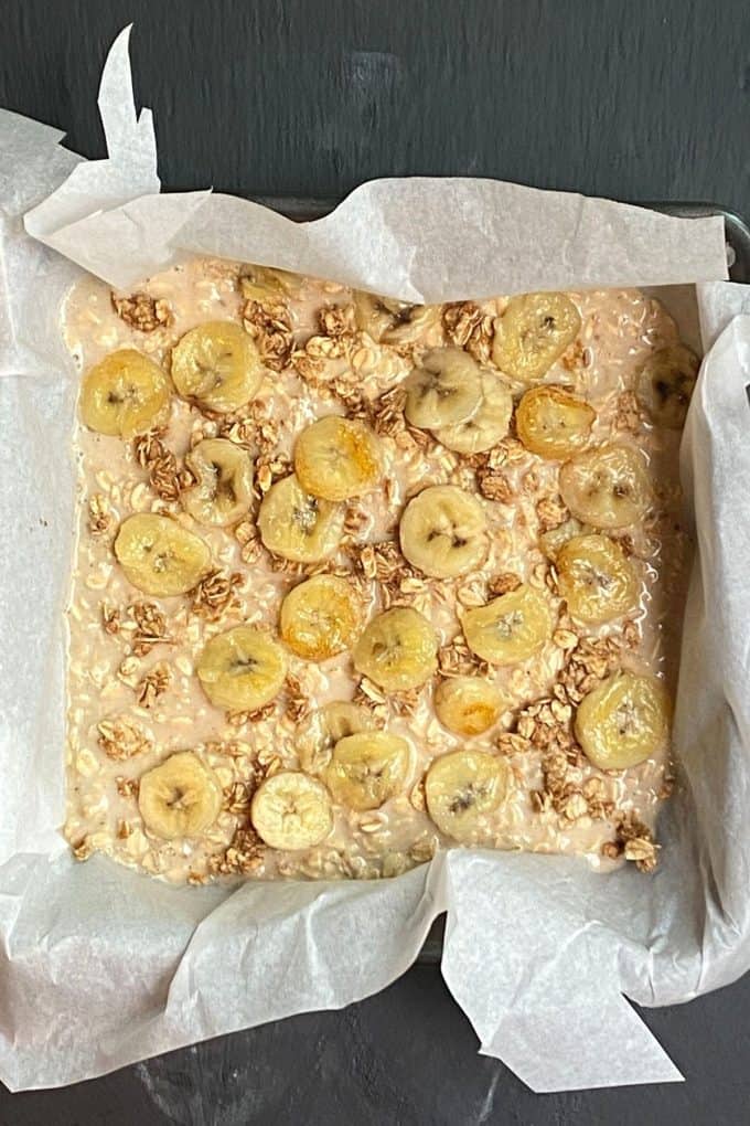 An overhead view of a baking pan lined with parchment paper and filled with peanut butter banana baked oatmeal ready to go into the oven