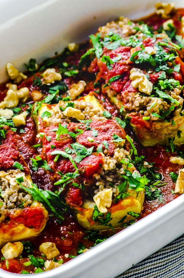 a close up view A white baking dish with Vegan Quinoa Stuffed Zucchini Boats