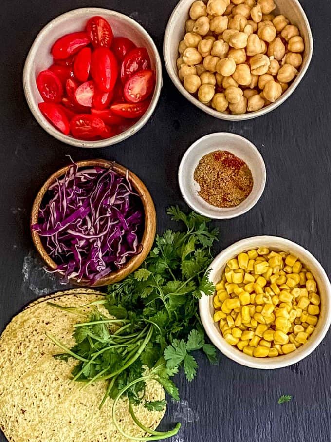 Ingredients to make chickpea tacos.  Chickpeas, corn, cabbage, tomatoes, spices ,cilantro and corn tortillas