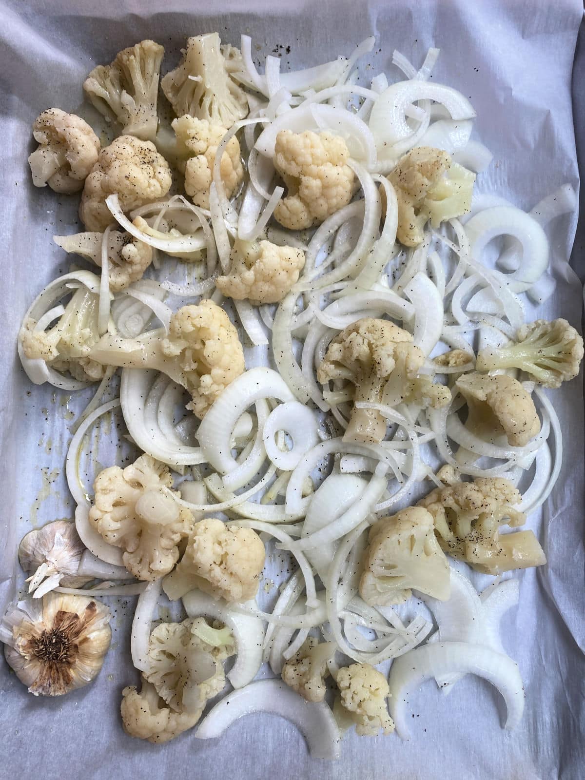 Raw Cauliflower, onions and garlic in a baking sheet