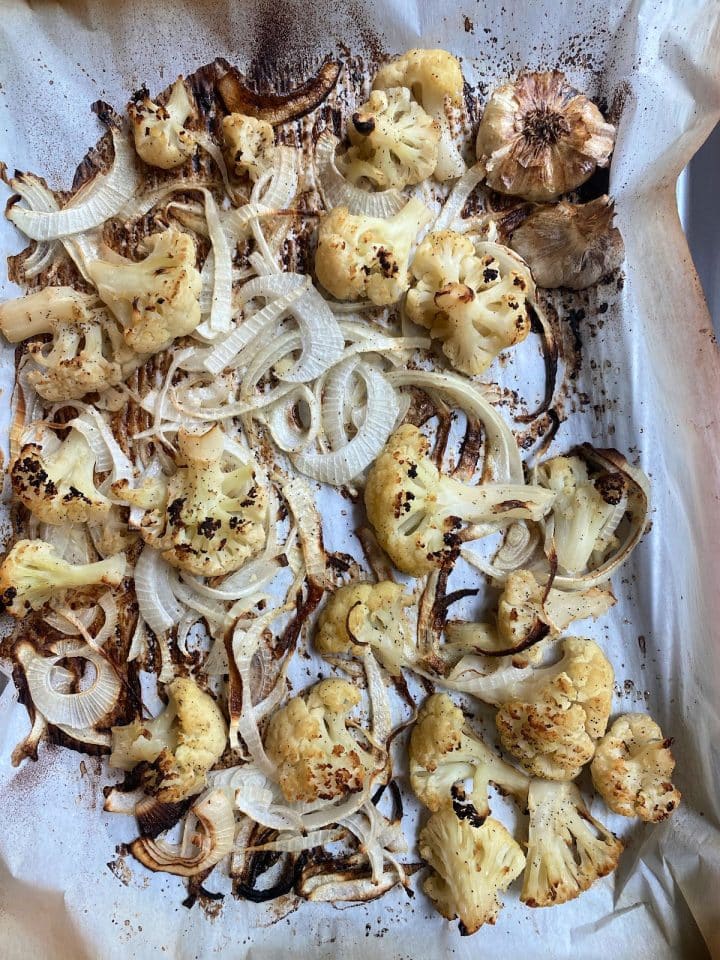 roasted cauliflower, onions and garlic on a baking sheet