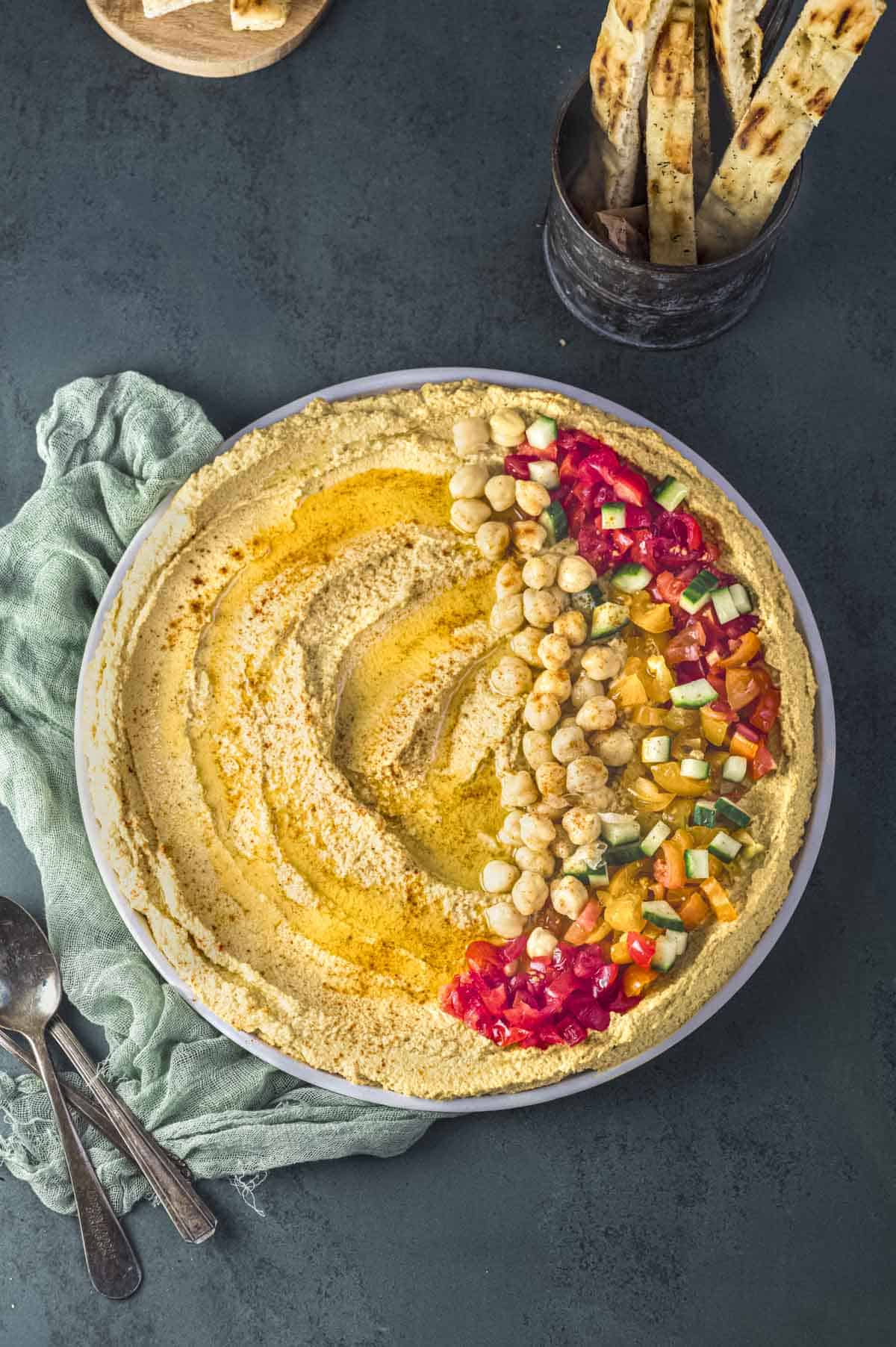 Overhead view of a plate with cauliflower hummus topped with tomatoes, cucumbers and chickpeas 