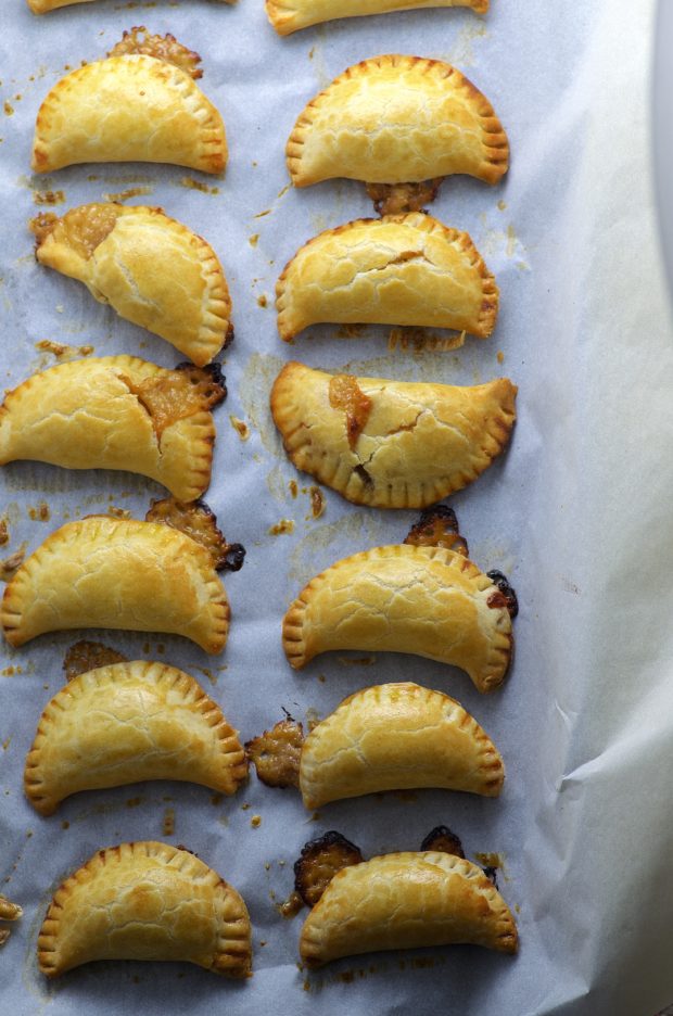 Baked fig and cheese empanadas on a baking sheets lined with parchment paper