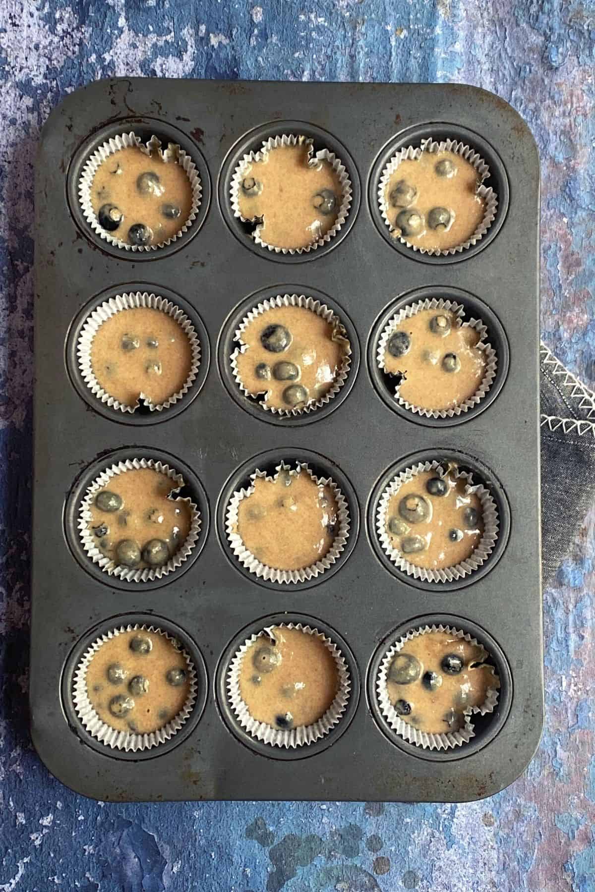 Overhead view of a muffin pan filled with blueberry corn bread muffins