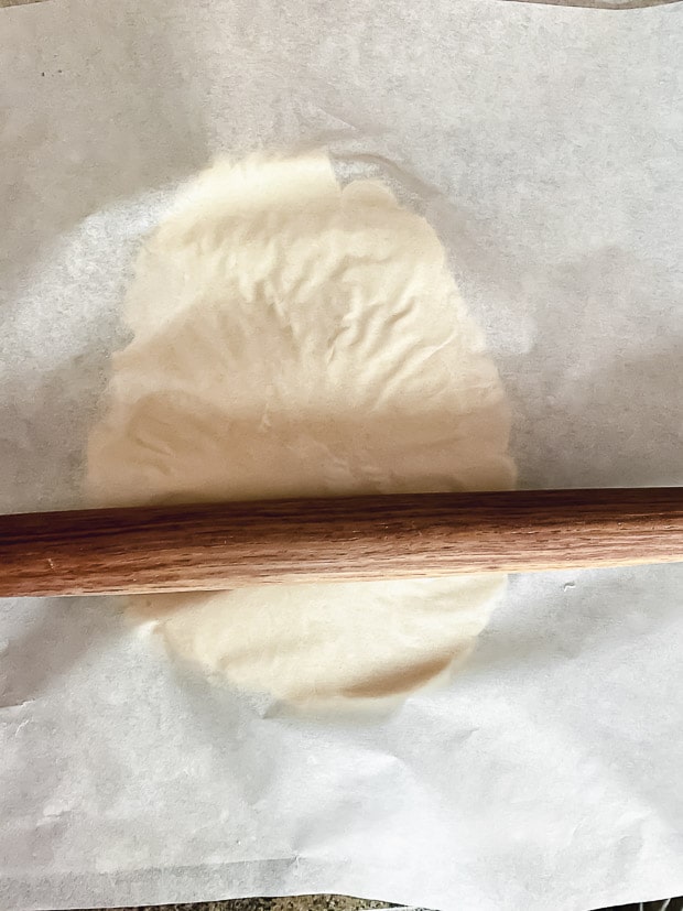 Rolling galette dough between two pieces of parchment paper