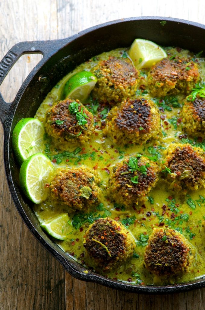 Cauliflower Quinoa Meatless Meatballs in Coconut Turmeric Broth in a cast iron pan with slices of lime