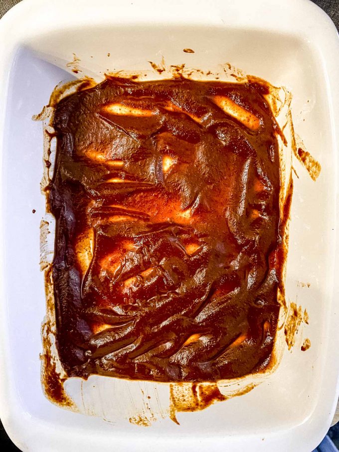 Spreading enchilada sauce at the bottom of a baking dish
