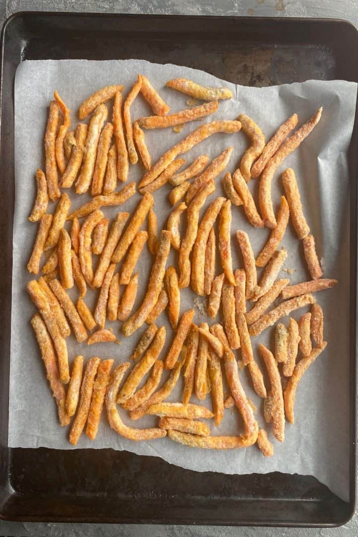 An overhead view of a baking sheet with parchment paper on it with sweet potato fries