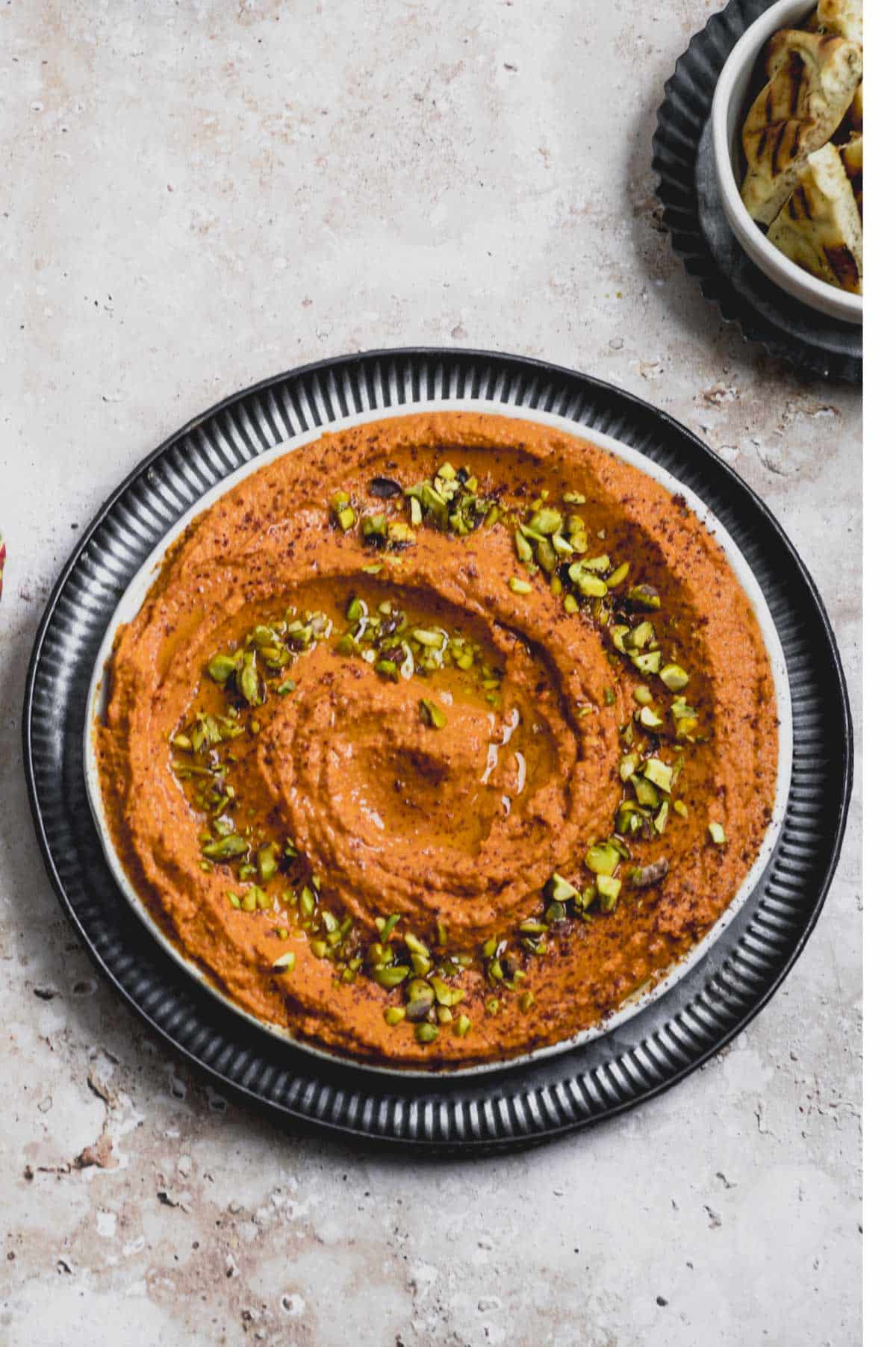 Roasted red pepper hummus on a plate garnishes with pistachios
