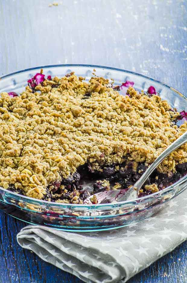 A round glass baking dish with blueberry crumble
