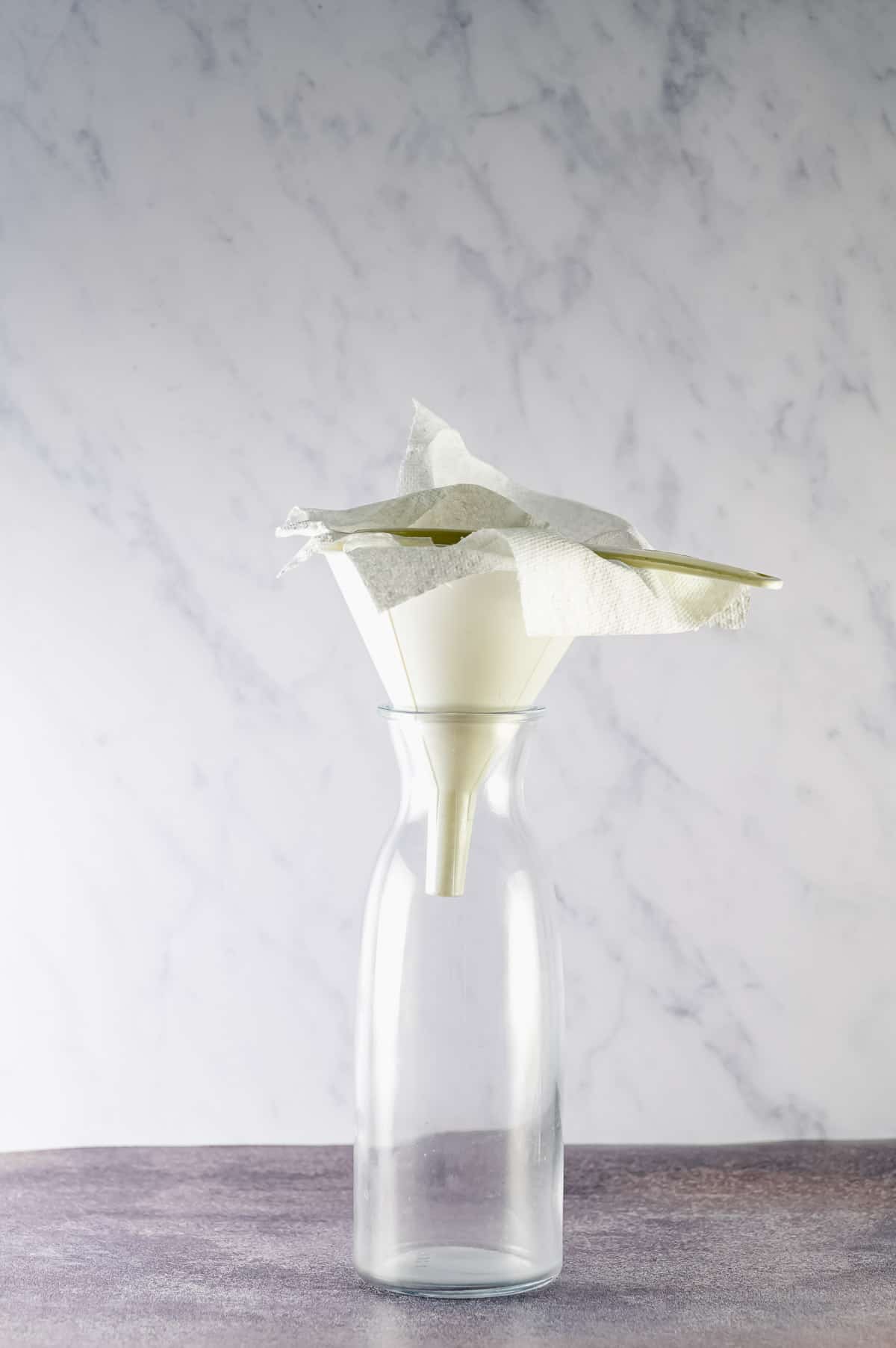 A glass bottle with a paper towel lined funnel