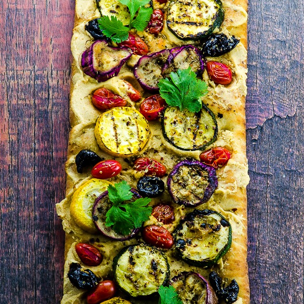 Close up with of a grilled pizza with vegetables and hummus
