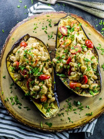 Two eggplant halves baked and filled with cooked fennel, white beans, tomatoes and parsley