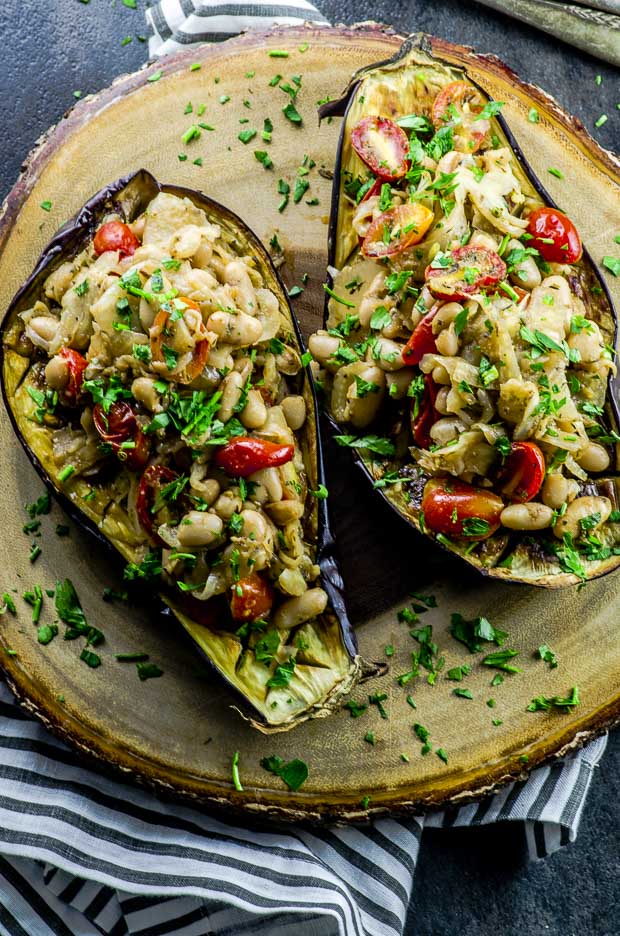 Overhead view of one eggplant sliced in half , roasted and topped with cooked fennel and cannellini beans