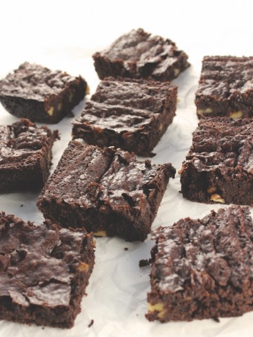 Squares of Fudgy Double Chocolate Brownies on a white parchment paper