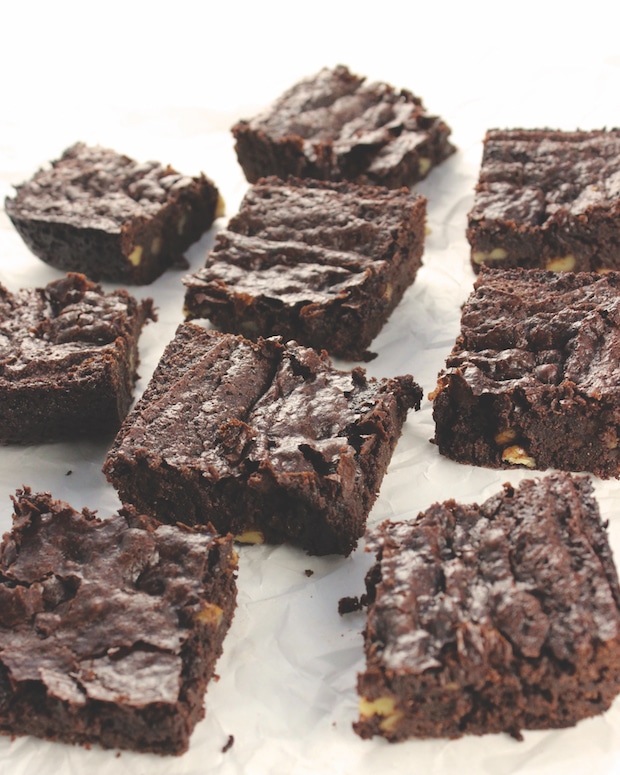 Squares of Fudgy Double Chocolate Brownies on a white parchment paper