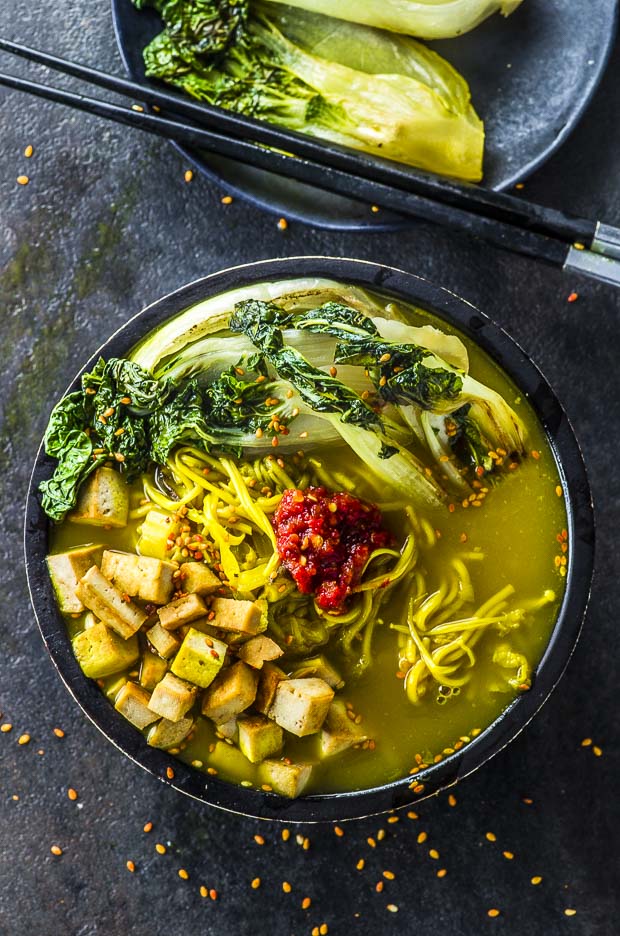 Birds eye view of a black bowl with Immune Booster Vegan Ramen. The vegan ramen is topped with seared baby boy choy, ramen noodles, spicy garlic sauce and saute tofu square.