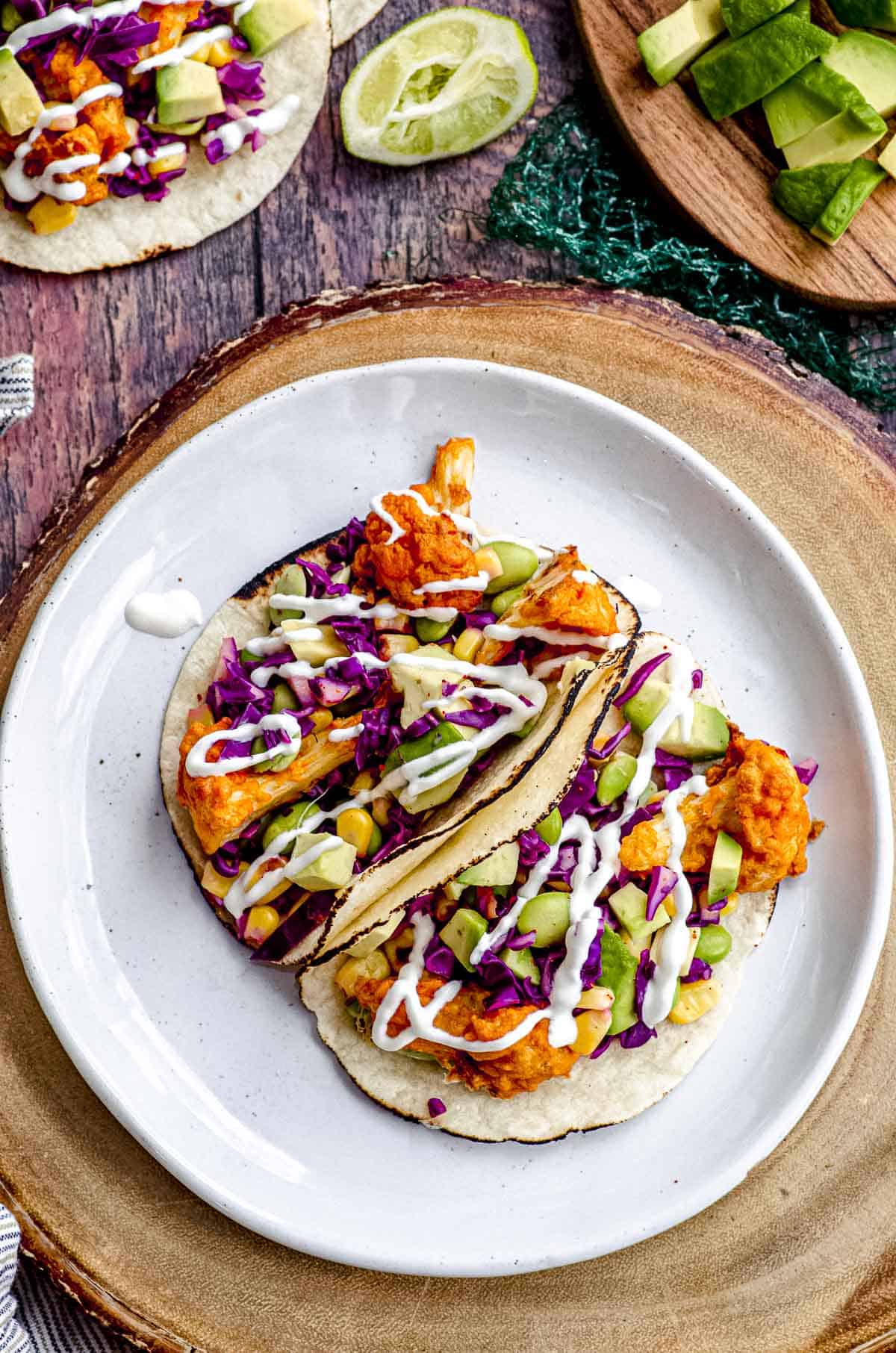 Overhead view of two vegan tacos on a white plate