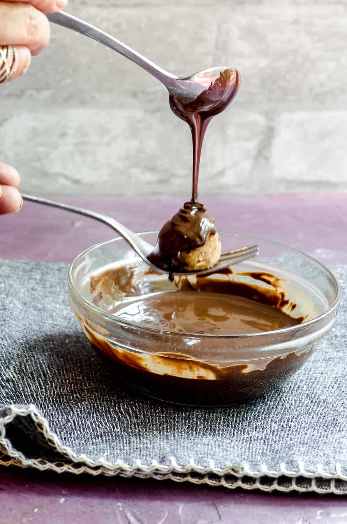 Pouring melted chocolate over a chickpea cookie dough balls