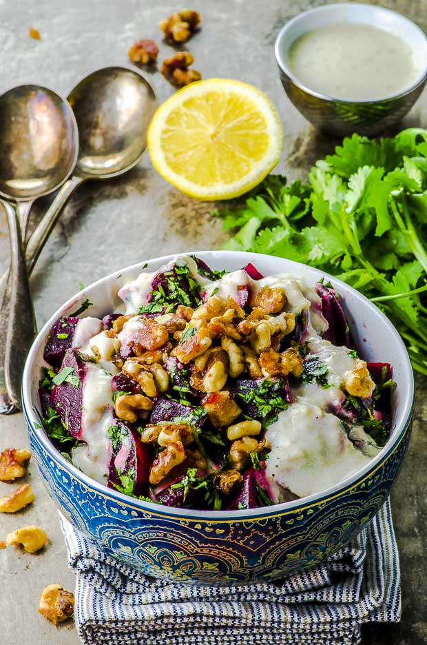 45 angle view of a blue bowl with beet salad with candied walnuts and horseradish dressing. One of our vegetarian Passover recipes.