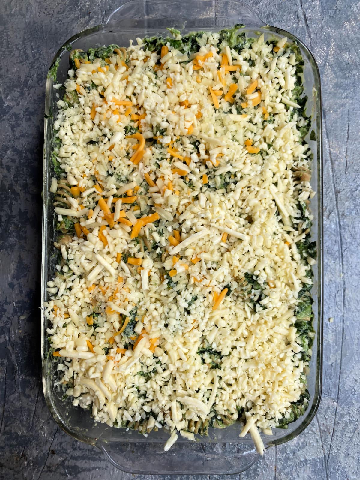 Creamed spinach and chickpea pasta in a baking dish topped with cheese