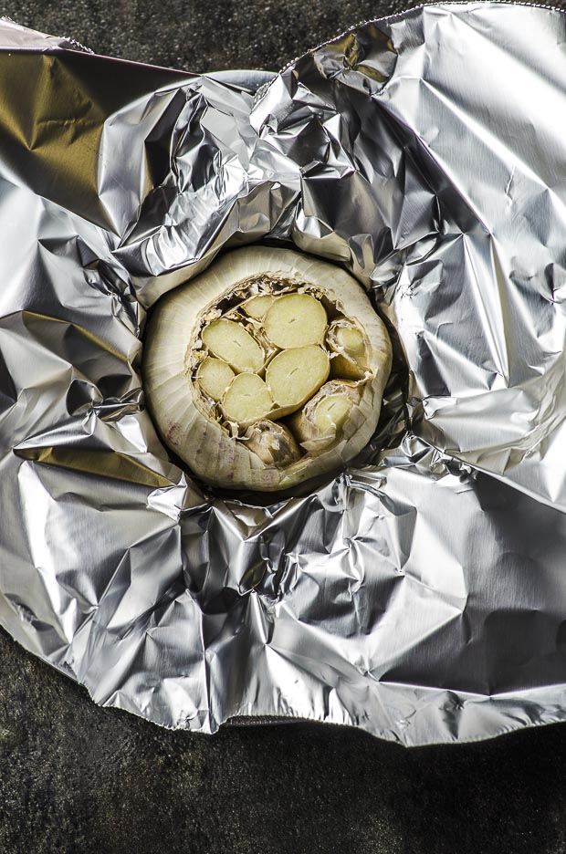 Raw head of garlic on a piece of aluminum foil