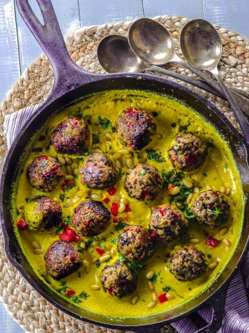 bird's-eye view of a cast iron skillet with Quinoa lentil meatballs with tahini turmeric sauce