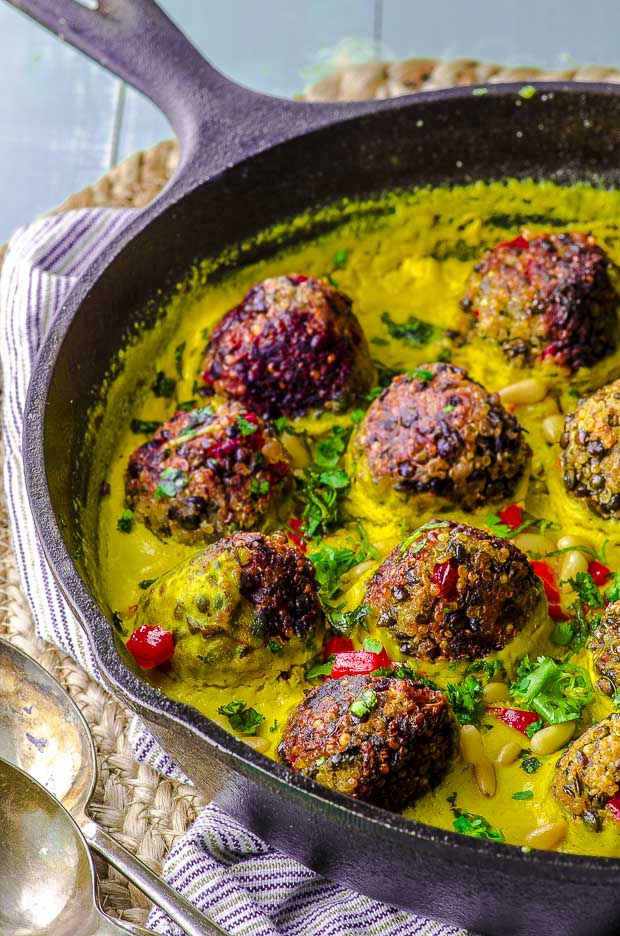 Side view of a cast iron skillet with Quinoa lentil meatballs with tahini turmeric sauce